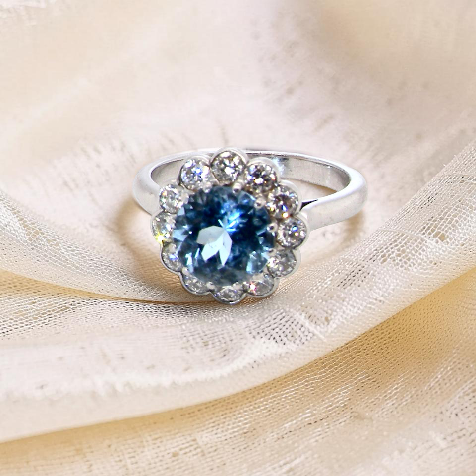 A fine vintage cluster ring centred with a deep blue aquamarine, measuring approximately 8mm and estimated at 2 carats,