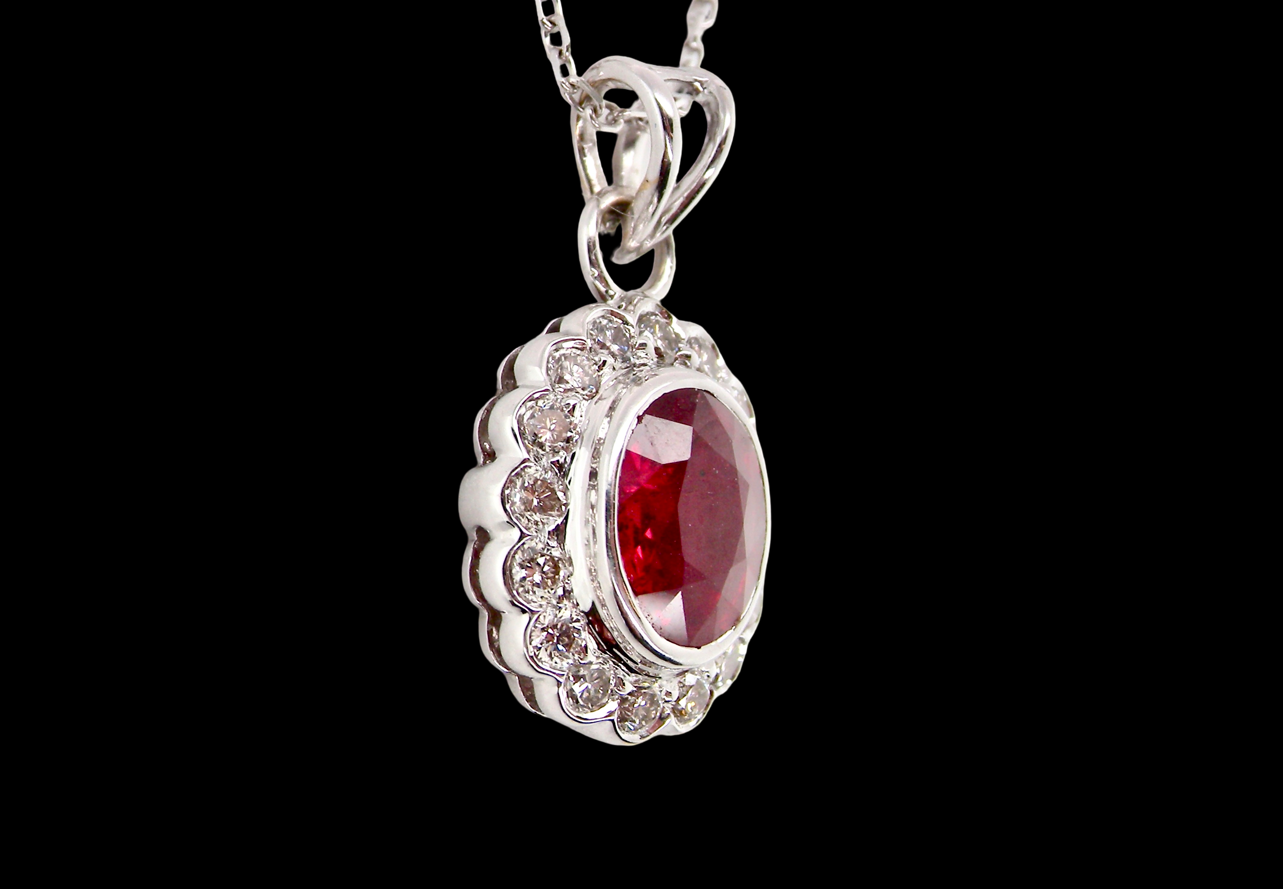 A fine white gold pendant that features to the centre an oval facet cut ruby, 8x6mm (est 1.25 carats) good deep red colour.
sidew