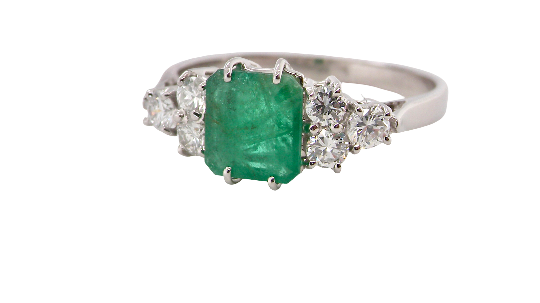 A fine white gold* ring that features a rectangular emerald centre stone, measures 6x6.5mm (est one carat), mid to dark green hue,