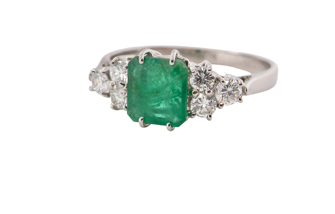 A fine white gold* ring that features a rectangular emerald centre stone, measures 6x6.5mm (est one carat), mid to dark green hue,