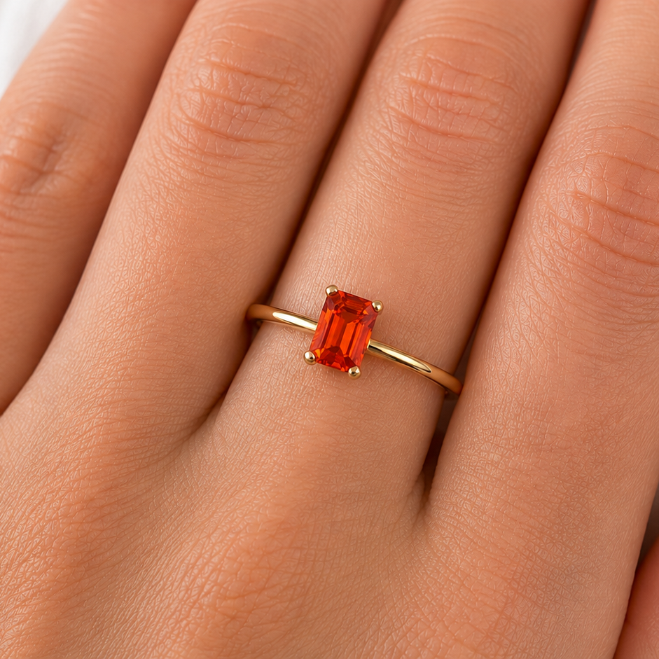A rectangular fire opal solitaire ring on a hand