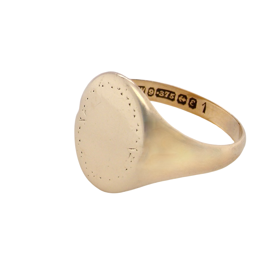 A gentlemans 9 carat gold signet ring. The head is oval with a pattern to the outer edges. 