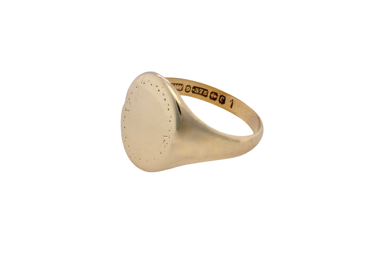 A gentlemans 9 carat gold signet ring. The head is oval with a slight pattern to the outer edges. 