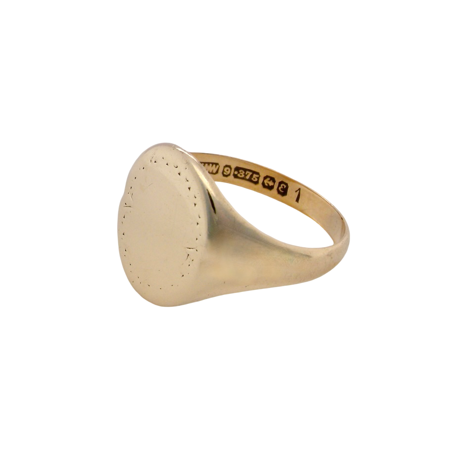 A gentlemans 9 carat gold signet ring. The head is oval with a slight pattern to the outer edges. 
