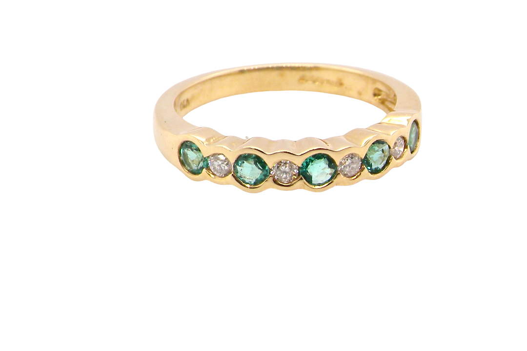 A half hoop eternity ring. Set with five round emeralds, each 3mm (0.10 carats) and set with an alternate brilliant cut white diamond,
