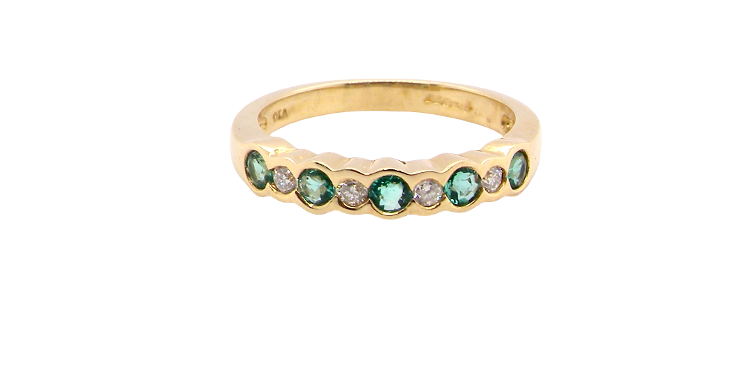 A half hoop eternity ring. Set with five round emeralds, each 3mm (0.10 carats) and set with an alternate brilliant cut white diamond, 2.4mm each (total 0.20 carats)