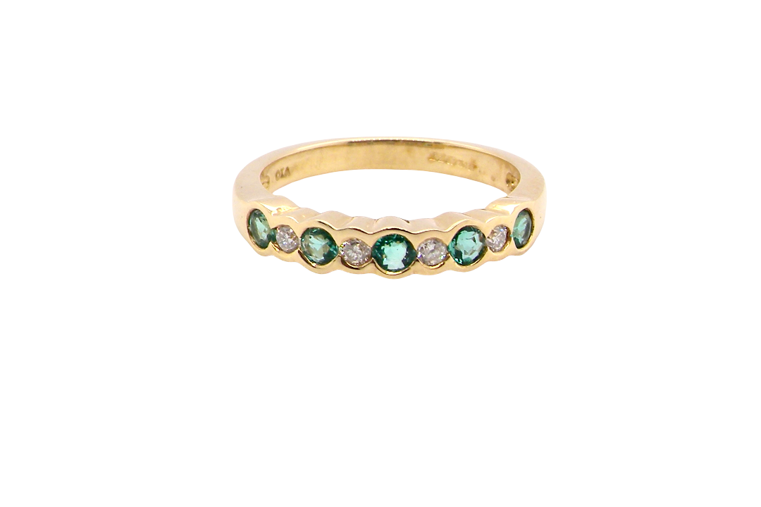 A half hoop eternity ring. Set with five round emeralds, each 3mm (0.10 carats) and set with an alternate brilliant cut white diamond, 2.4mm each (total 0.20 carats)
