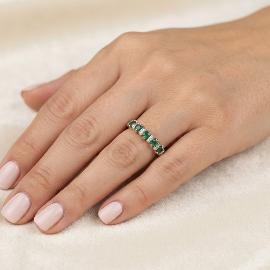 hand A half hoop ring, stamped 750 (testing as 18 carat gold)
Set with alternate gemstones, five bright green emeralds