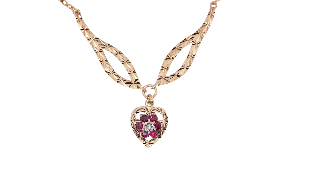 A late 1970s pendant/necklace. Features a heart shaped pendant that has a cluster set to its centre. Six small rubies 2.3mm each surround a diamond. Diamond cut outer rim.