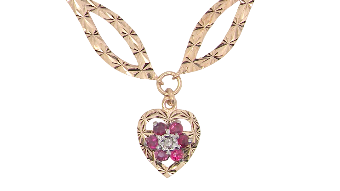 A late 1970s pendant/necklace. Features a heart shaped pendant that has a cluster set to its centre. Six small rubies 2.3mm each surround an illusion set diamond.