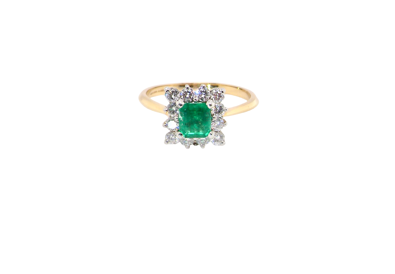 A lovely cluster ring that features to the centre a rectangle shaped emerald, 7x5mm. Shows a deep grass green colour which does have natural inclusions common with most emeralds, but the depth of colour is impressive.
