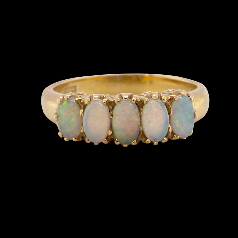 A lovely five stone ring. Set with five oval white opals, each 5x3.5mm, good play of colour on all.