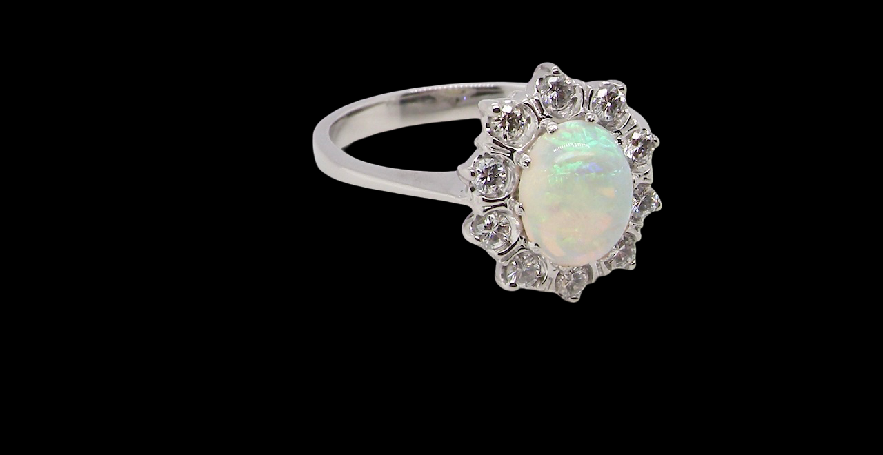 A lovely white gold cluster ring. Features to the centre an oval white opal, 9x7mm,