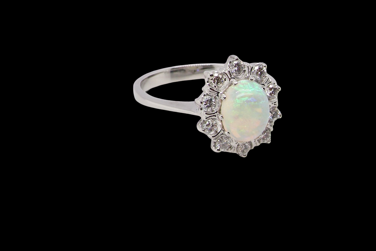 A lovely white gold cluster ring. Features to the centre an oval white opal, 9x7mm,