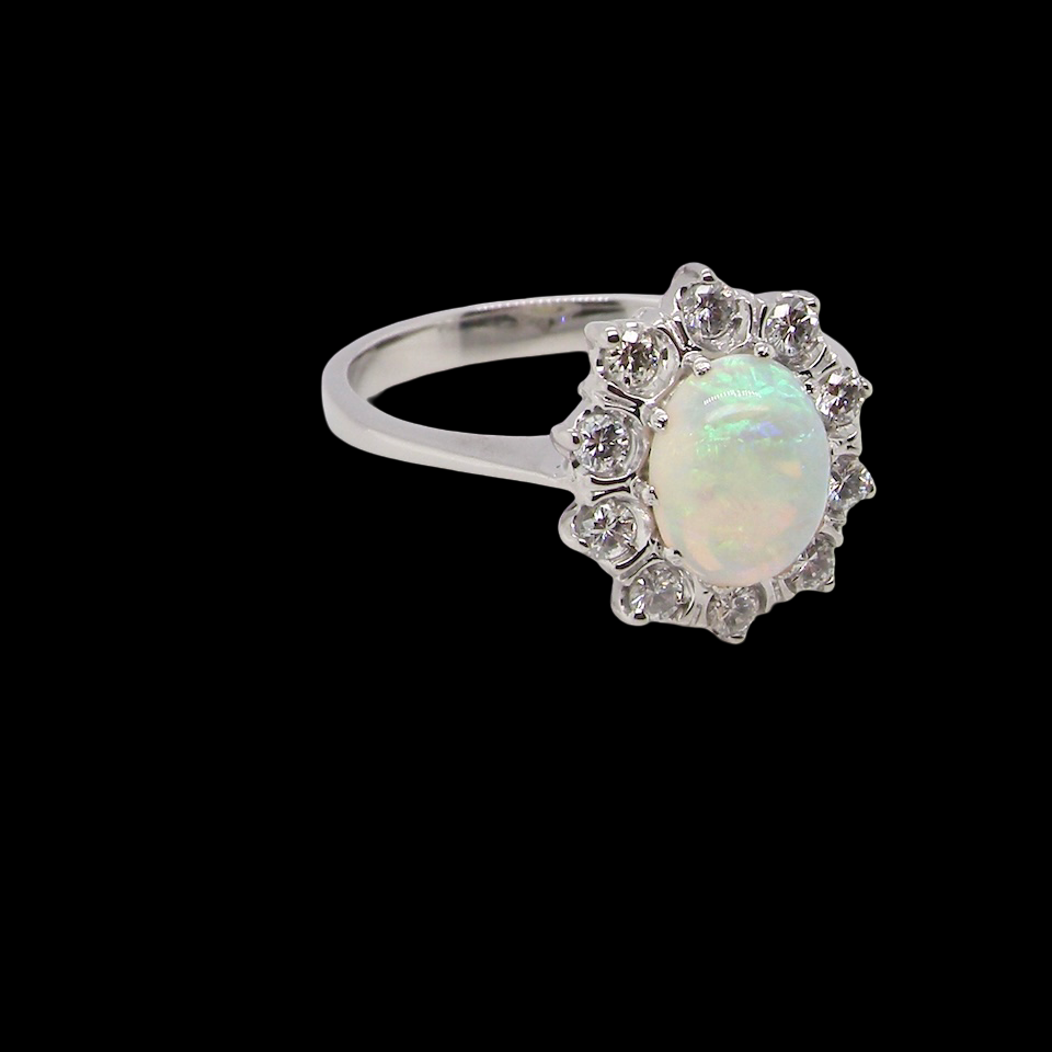 A lovely white gold cluster ring. Features to the centre an oval white opal, 9x7mm,