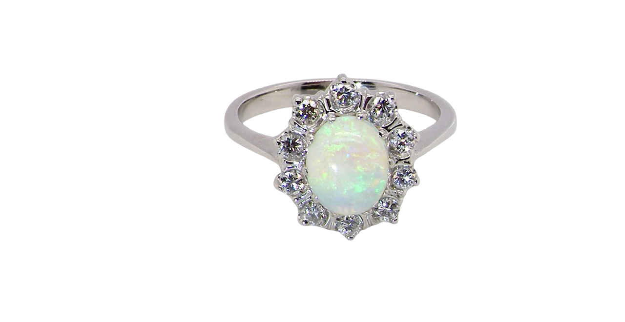 A lovely white gold cluster ring. Features to the centre an oval white opal, 9x7mm, with an excellent play of colour.