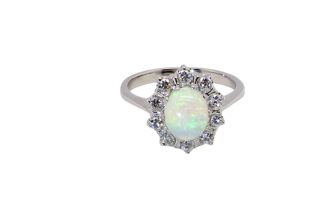 A lovely white gold cluster ring. Features to the centre an oval white opal, 9x7mm, with an excellent play of colour.