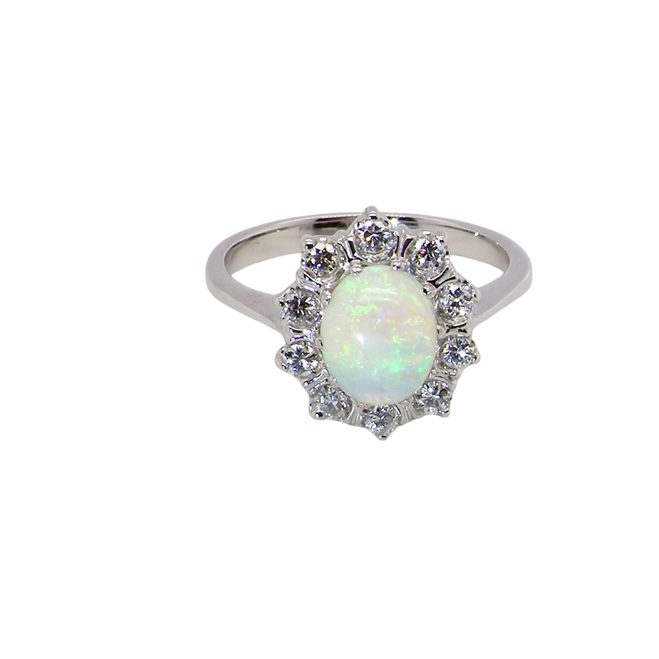 A lovely white gold cluster ring. Features to the centre an oval white opal, 9x7mm, with an excellent play of colour.