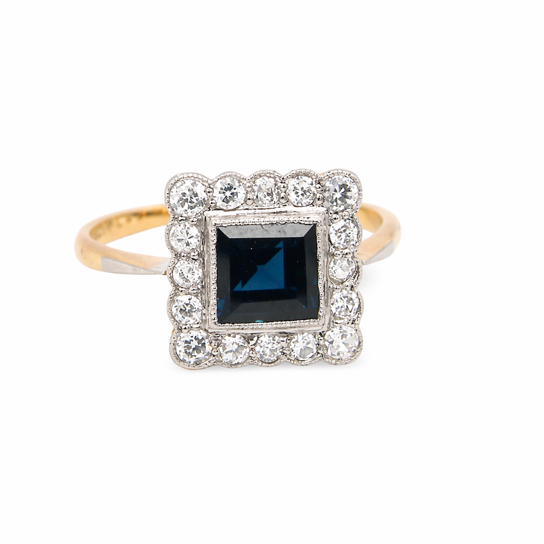 A mid 20th century cluster ring. Features a square dark blue sapphire 5x5mm (est 0.60 carats) mille grain setting in platinum. 