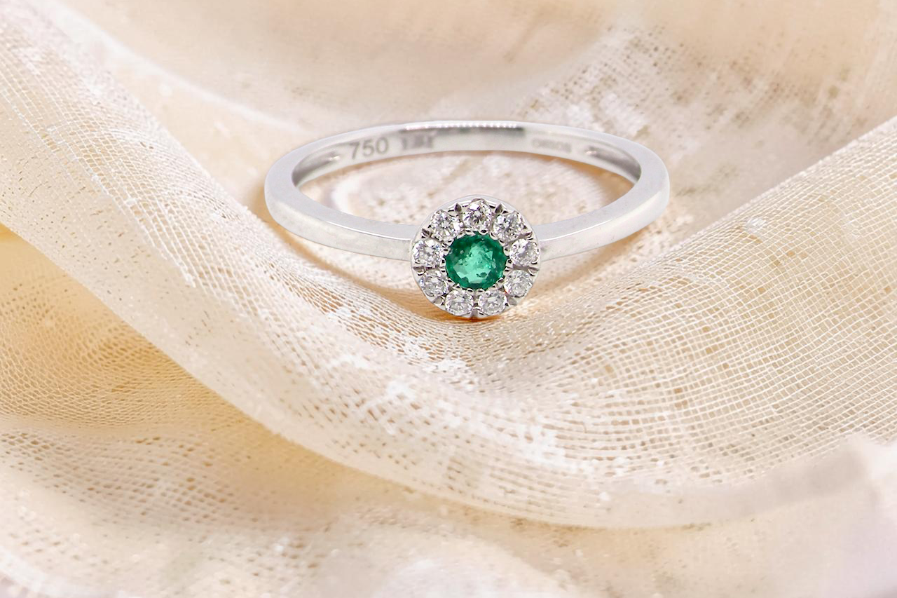 A mini cluster fashioned in 18 carat white gold. The round emerald measures 2.7mm 