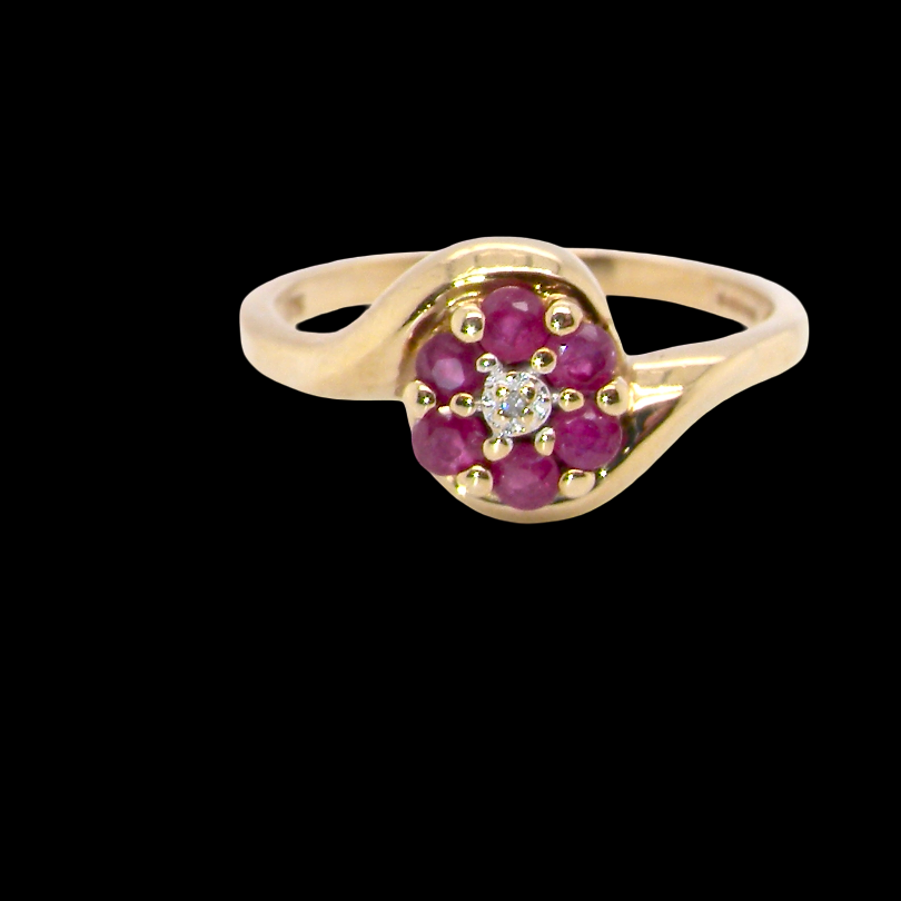 A modern 9 carat gold cluster ring. At the centre a small diamond, this complimented by an outer halo of six 2.4mm rubies