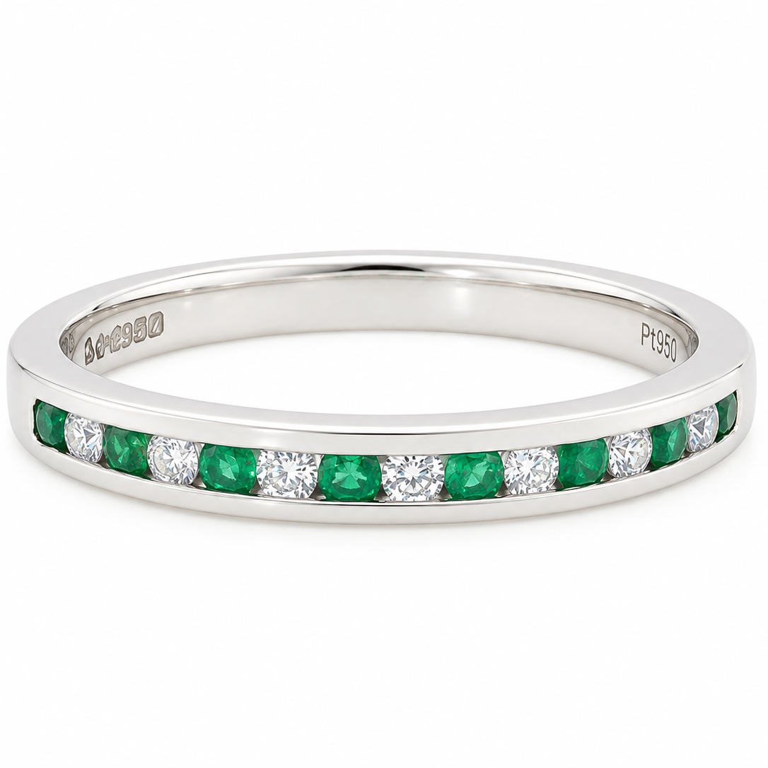 A ring featuring a channel setting of round-cut green emeralds and clear diamonds, shown on a plain white background.
