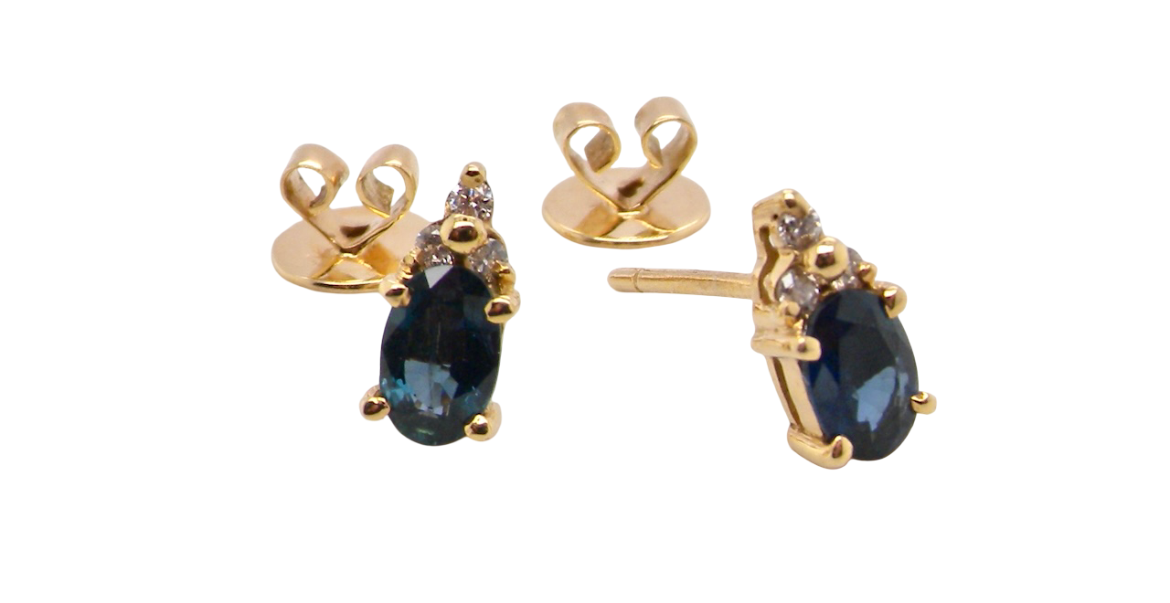 A pair of 18 carat gold earrings*. Set with a dark blue oval cut sapphire 6x4mm, claw set.
Above each, three small white diamonds, overall size 9x4.6mm,