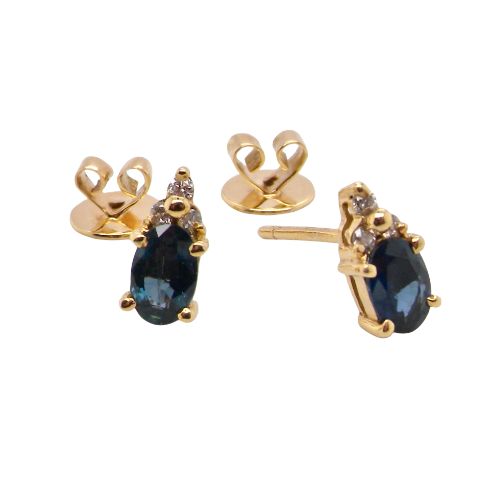 A pair of 18 carat gold earrings*. Set with a dark blue oval cut sapphire 6x4mm, claw set.
Above each, three small white diamonds, overall size 9x4.6mm,