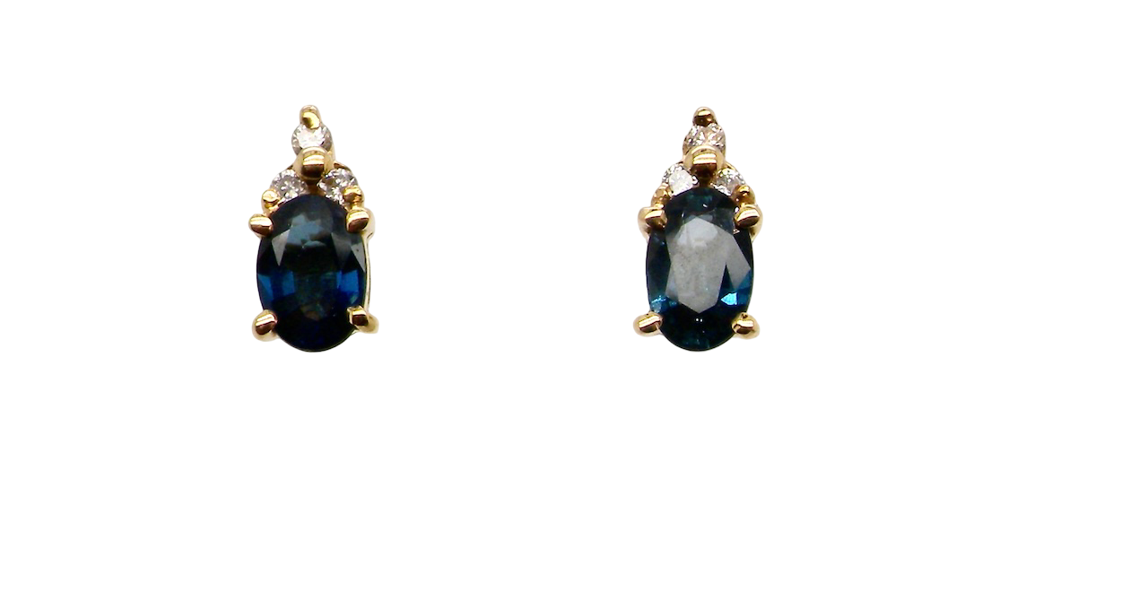 A pair of 18 carat gold earrings*. Set with a dark blue oval cut sapphire 6x4mm, claw set.
Above each, three small white diamonds, overall size 9x4.6mm, weight each 1 gram.
