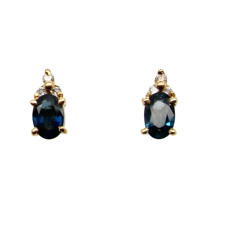 A pair of 18 carat gold earrings*. Set with a dark blue oval cut sapphire 6x4mm, claw set.
Above each, three small white diamonds, overall size 9x4.6mm, weight each 1 gram.