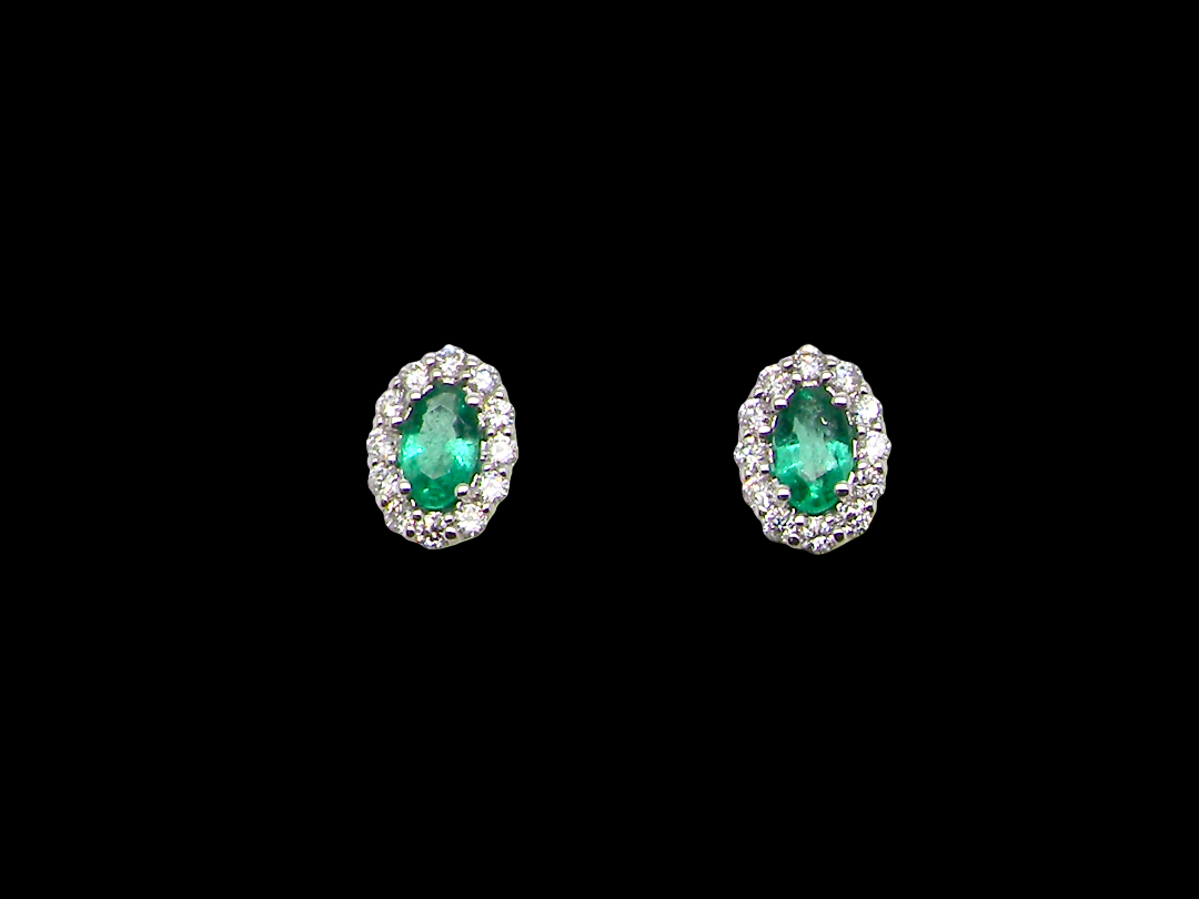 A pair of oval stud earrings featuring marquise-cut green emeralds surrounded by small clear stones in a silver-toned setting, presented on a solid black background.