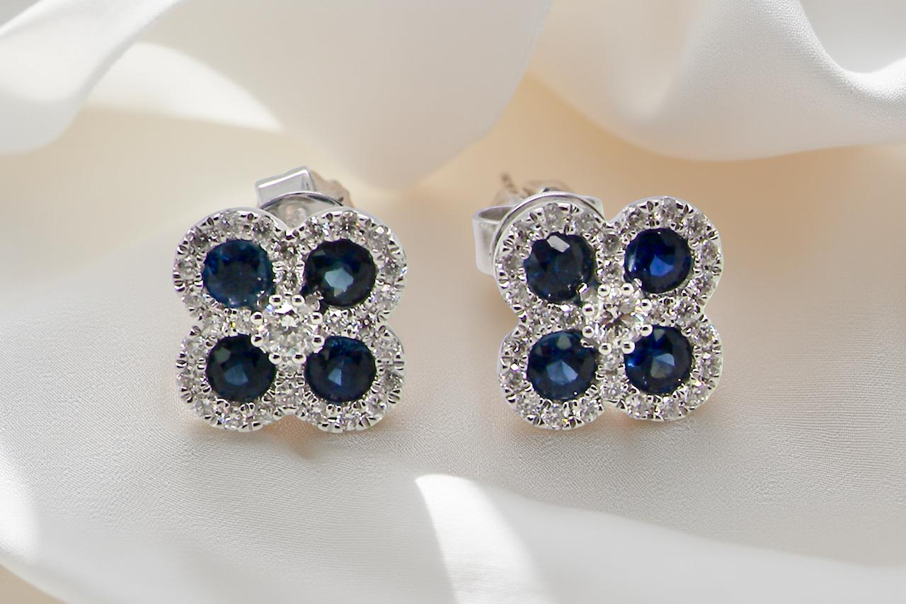 Pair of earrings with blue gemstones and clear stones on a white surface