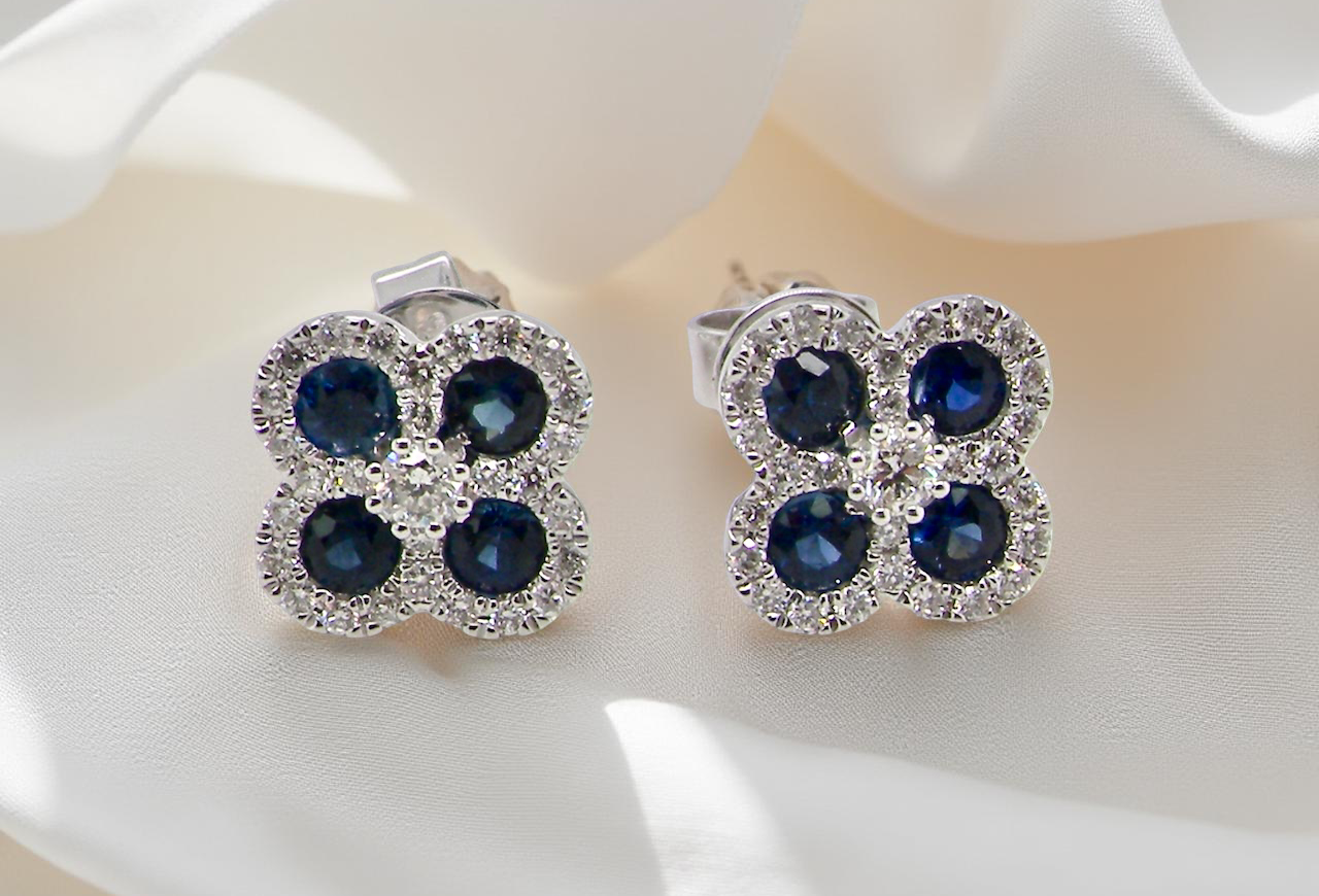 Pair of earrings with blue gemstones and clear stones on a white surface