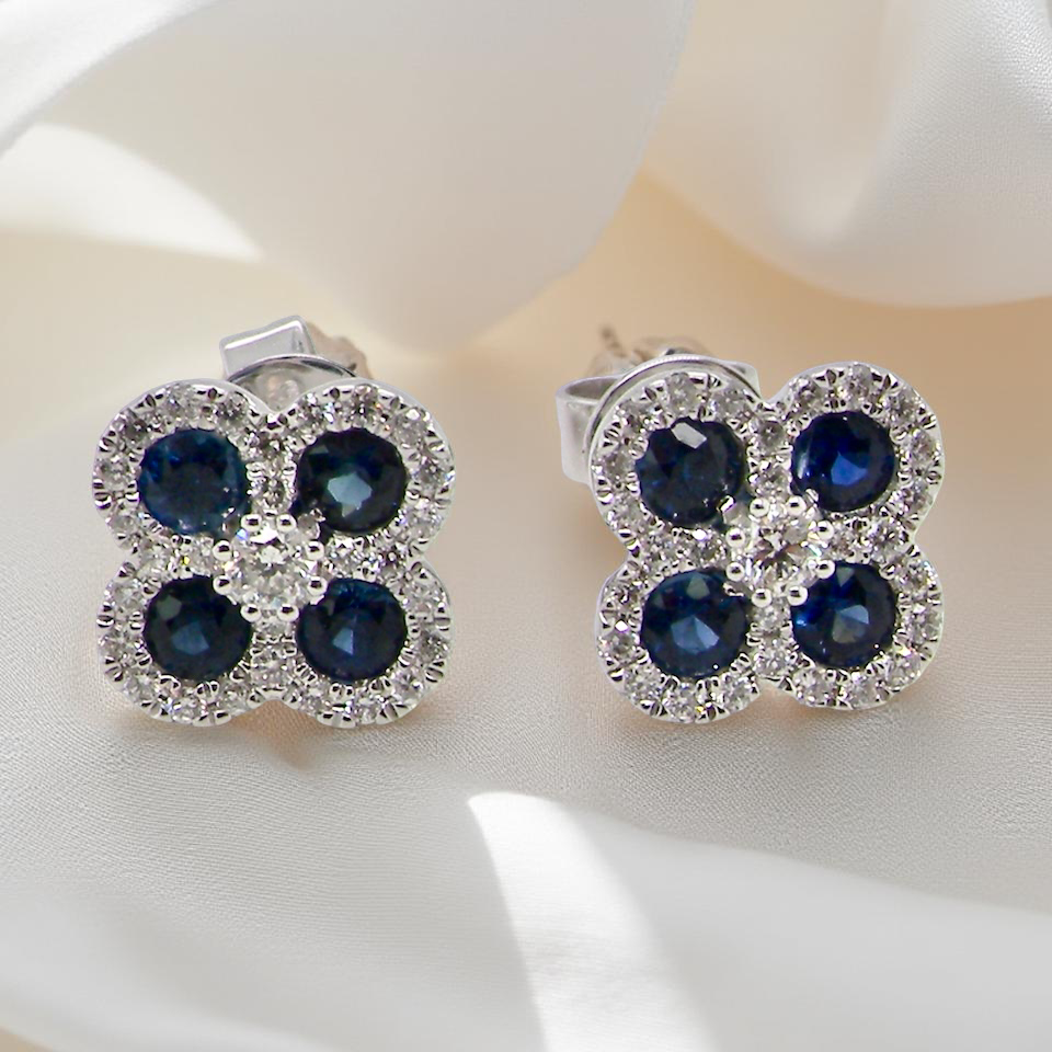 Pair of earrings with blue gemstones and clear stones on a white surface