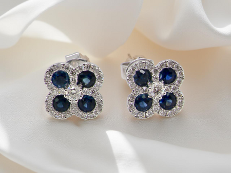 Pair of earrings with blue gemstones and clear stones on a white surface