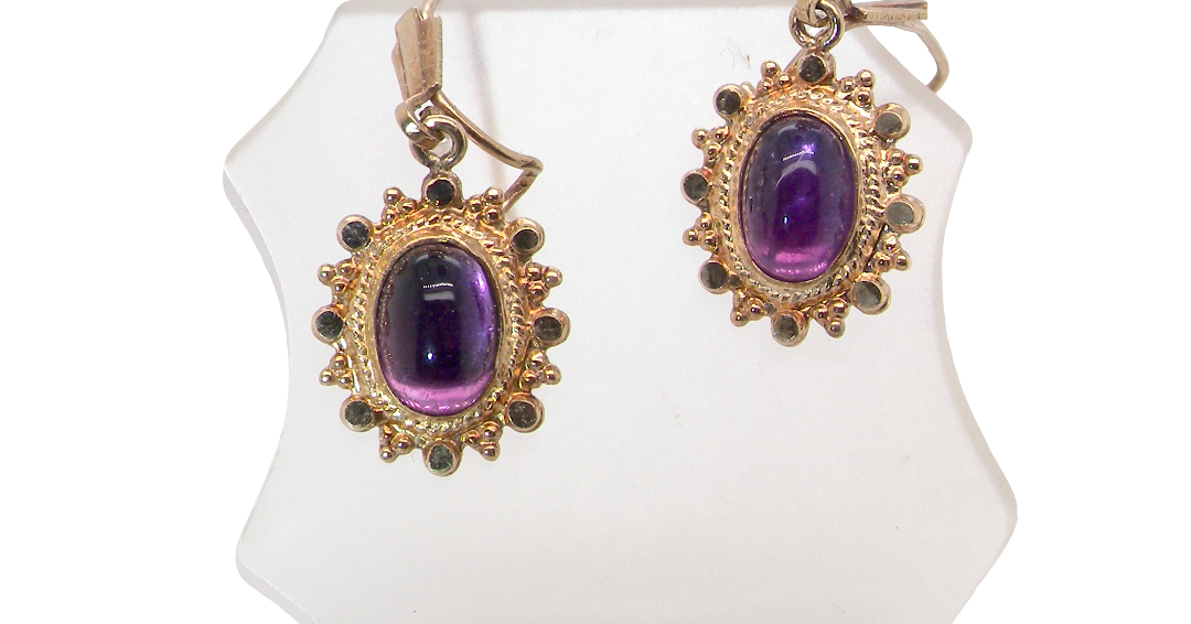 A pair of drop earrings. Each set with a cabouchon cut amethyst 6x4mm and set with an antique look border.