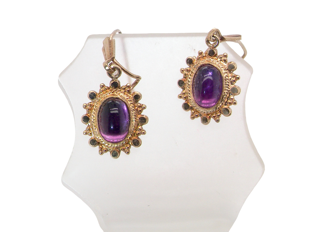 A pair of drop earrings. Each set with a cabouchon cut amethyst 6x4mm and set with an antique look border.