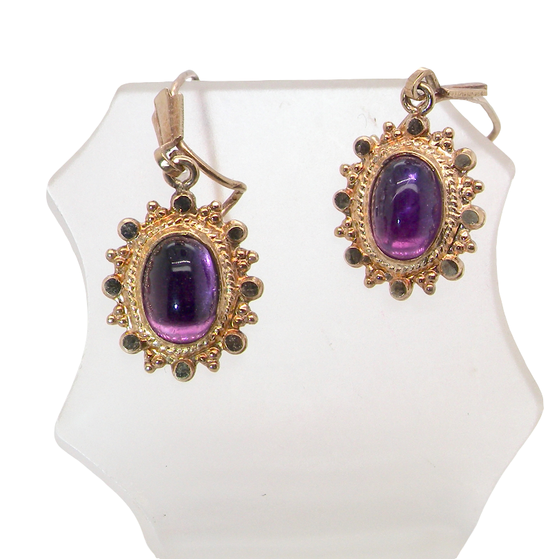 A pair of drop earrings. Each set with a cabouchon cut amethyst 6x4mm and set with an antique look border.