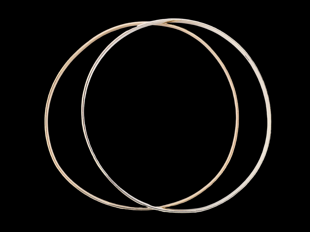 A pair of solid 9 carat gold bangles, featuring one in white gold and one in yellow gold. These classic circular bangles are timeless, elegant pieces that can be worn individually or stacked together for a contemporary layered look.