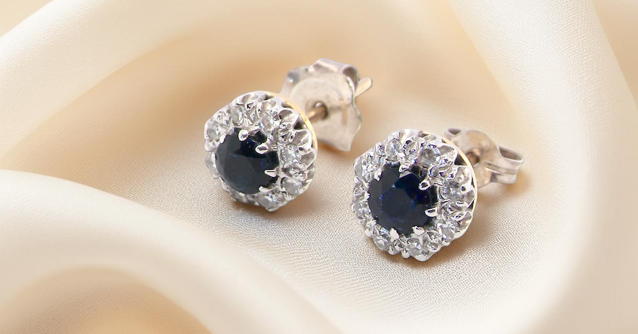 A pair of stud cluster earrings. Each earring is set with a dark blue sapphire centre .
Measures 4mm, surrounded by an outer halo of 1.3mm diamonds
