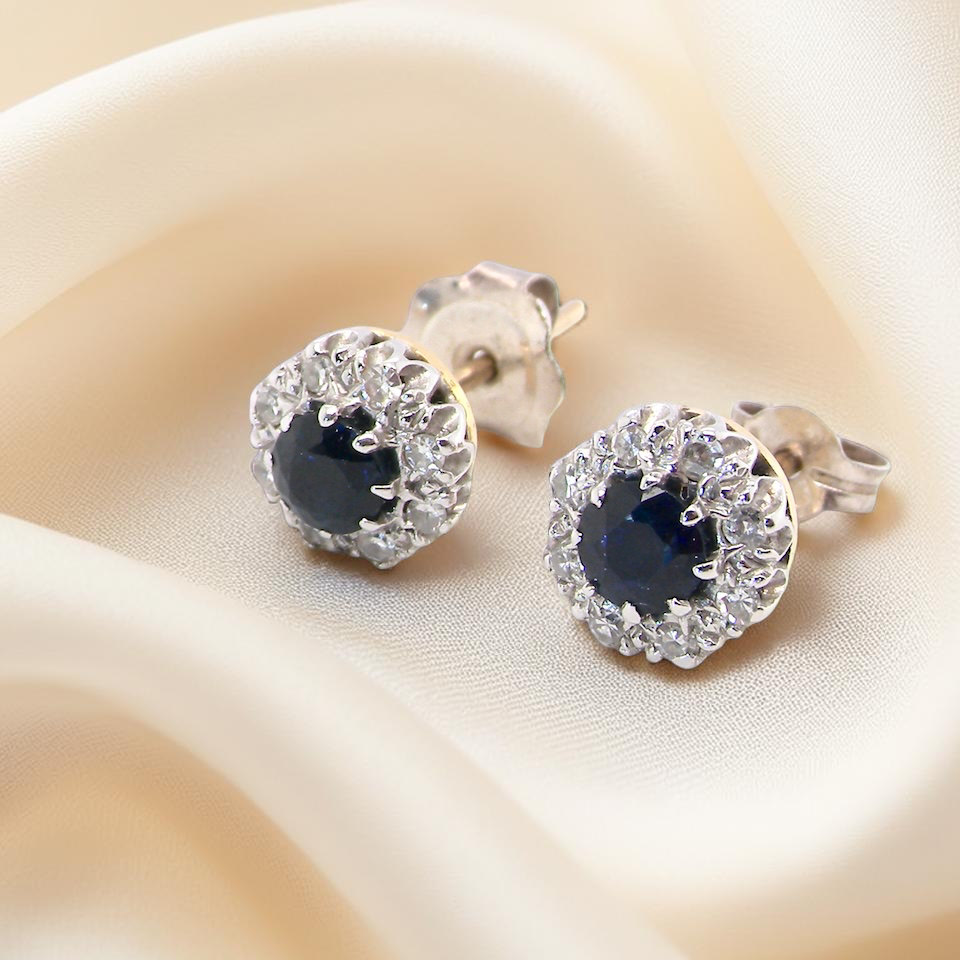 A pair of stud cluster earrings. Each earring is set with a dark blue sapphire centre .
Measures 4mm, surrounded by an outer halo of 1.3mm diamonds