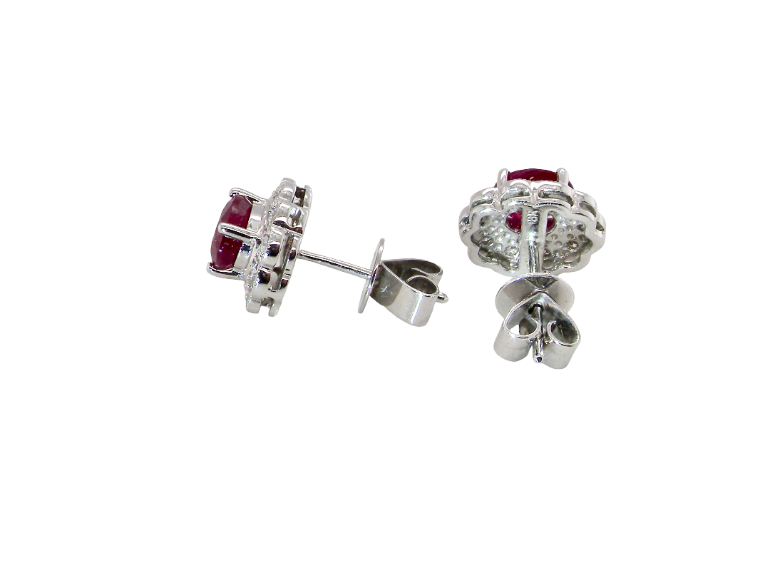 side A pair of white gold earrings, each set with an oval ruby 6x4.9mm (est 0.60 carats) complimented by an outer halo of ten 1.5mm diamonds