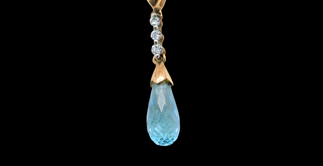 A pendant and earring set. The pendant has a pear shaped facet cut blue topaz 10x5mm. Above this three brilliant cut white cubic zirconia stones ,mm.
