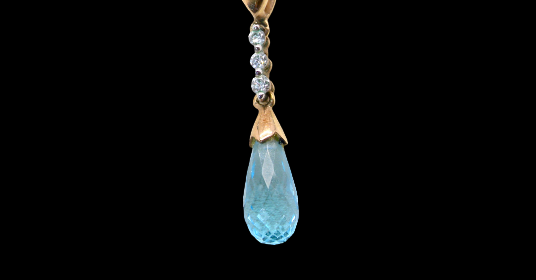 A pendant and earring set. The pendant has a pear shaped facet cut blue topaz 10x5mm. Above this three brilliant cut white cubic zirconia stones ,mm.