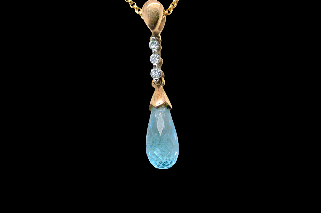 A pendant and earring set. The pendant has a pear shaped facet cut blue topaz 10x5mm. Above this three brilliant cut white cubic zirconia stones ,mm.