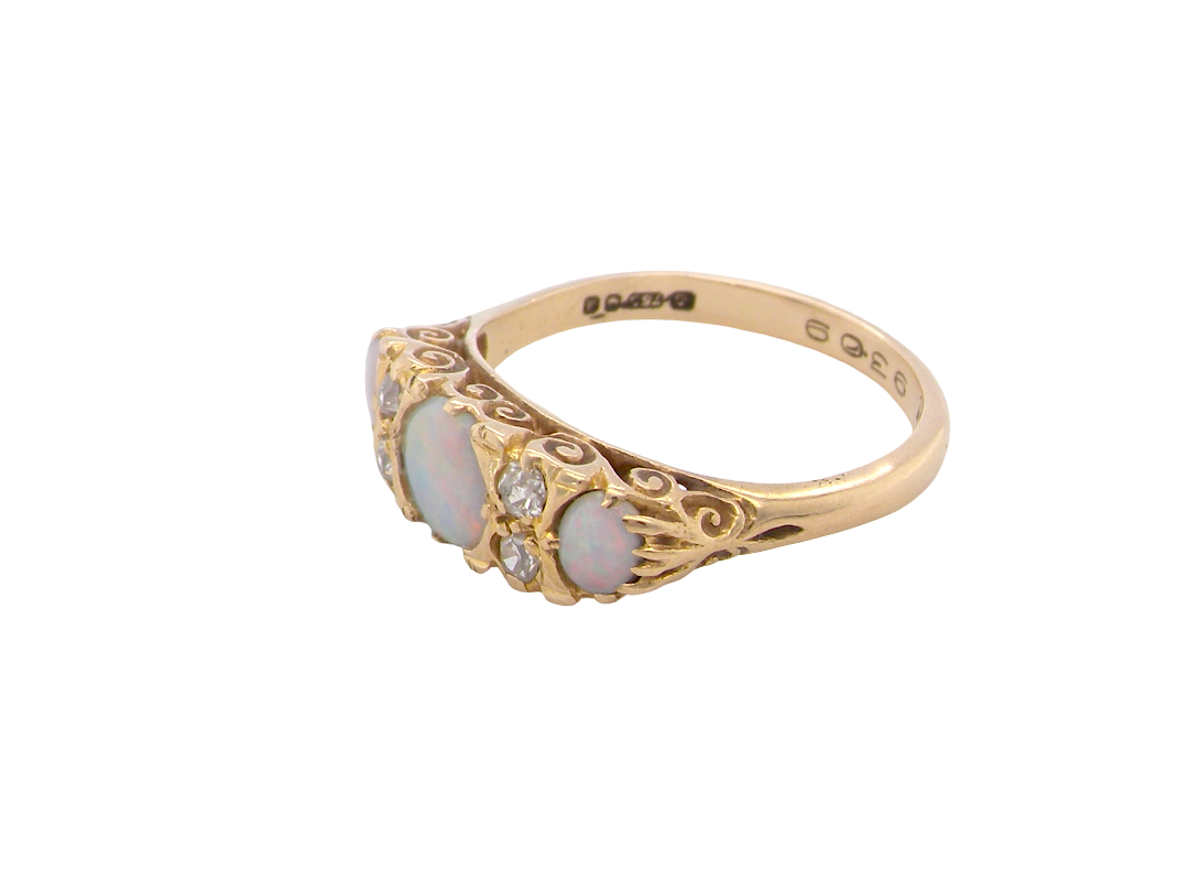 A pretty Victorian style ring. 18 carat gold. There are three opals, centre 6mm, each end 4x3mm. Good colour play side