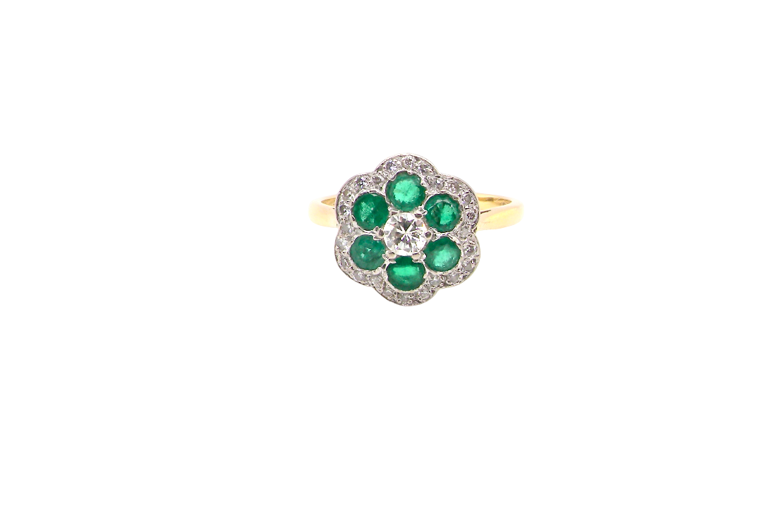 A pretty cluster ring. Features emeralds and diamonds. Centre stone a brilliant cut white diamond, (0.25 carats). 