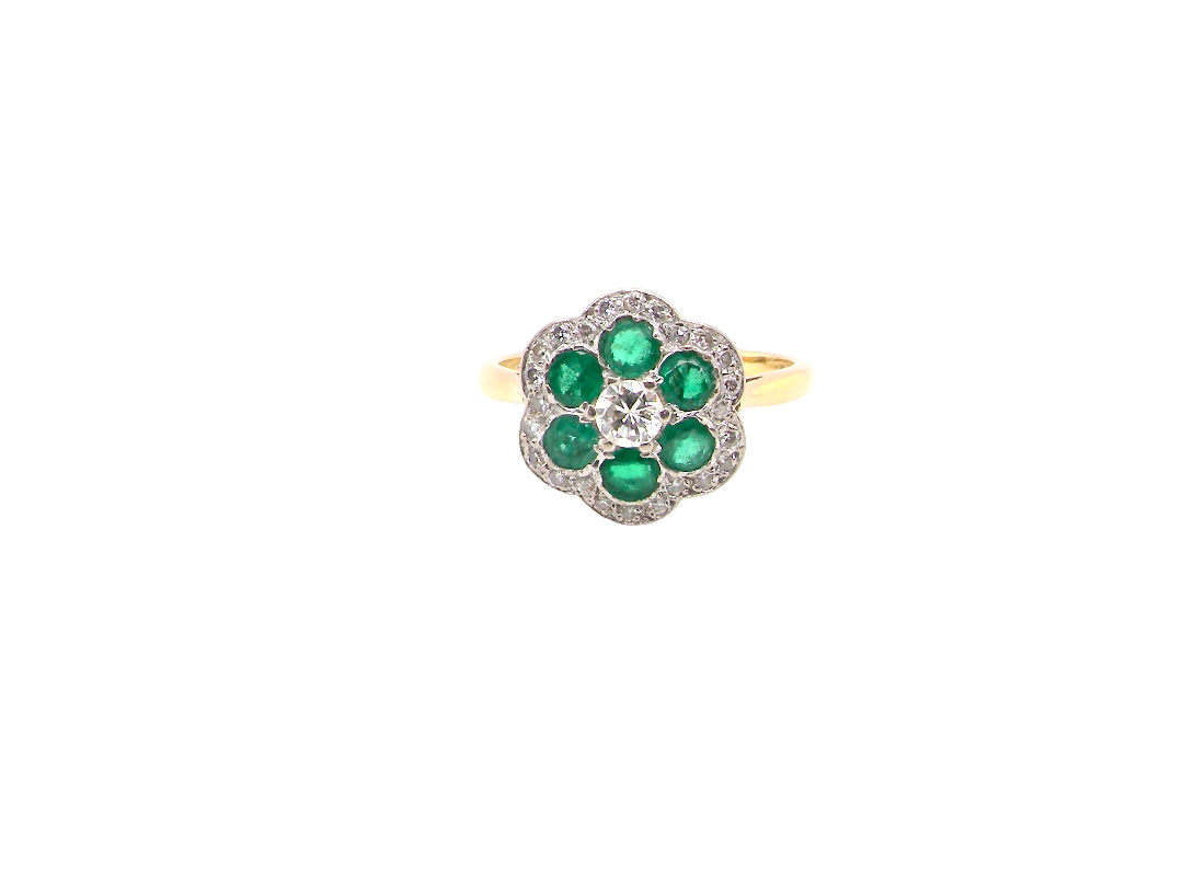 A pretty cluster ring. Features emeralds and diamonds. Centre stone a brilliant cut white diamond, (0.25 carats). 