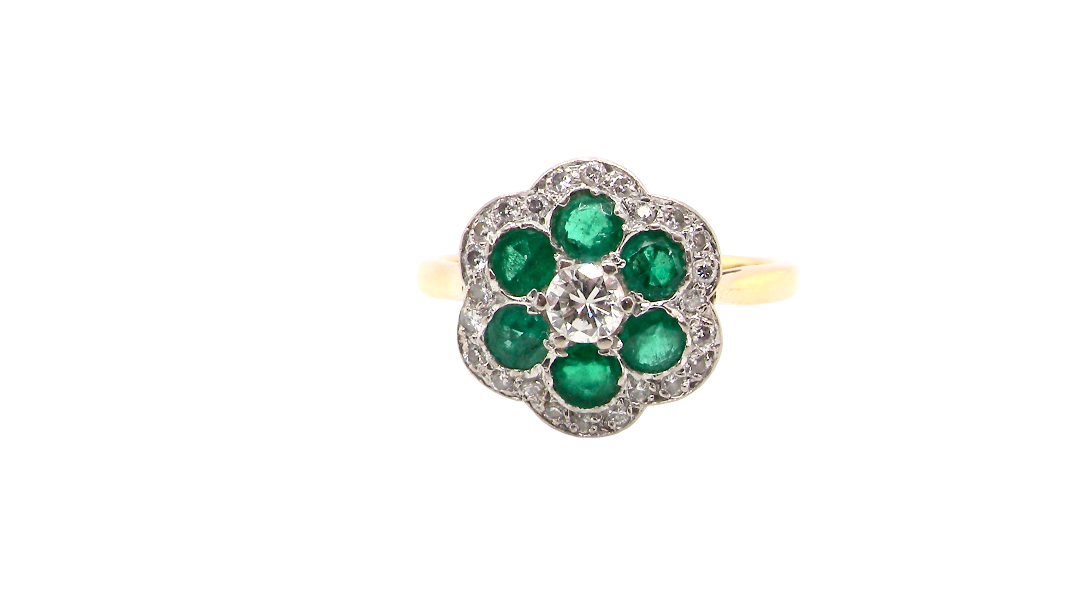 A pretty cluster ring. Features emeralds and diamonds. Centre stone a brilliant cut white diamond, measures 4mm (0.25 carats). 