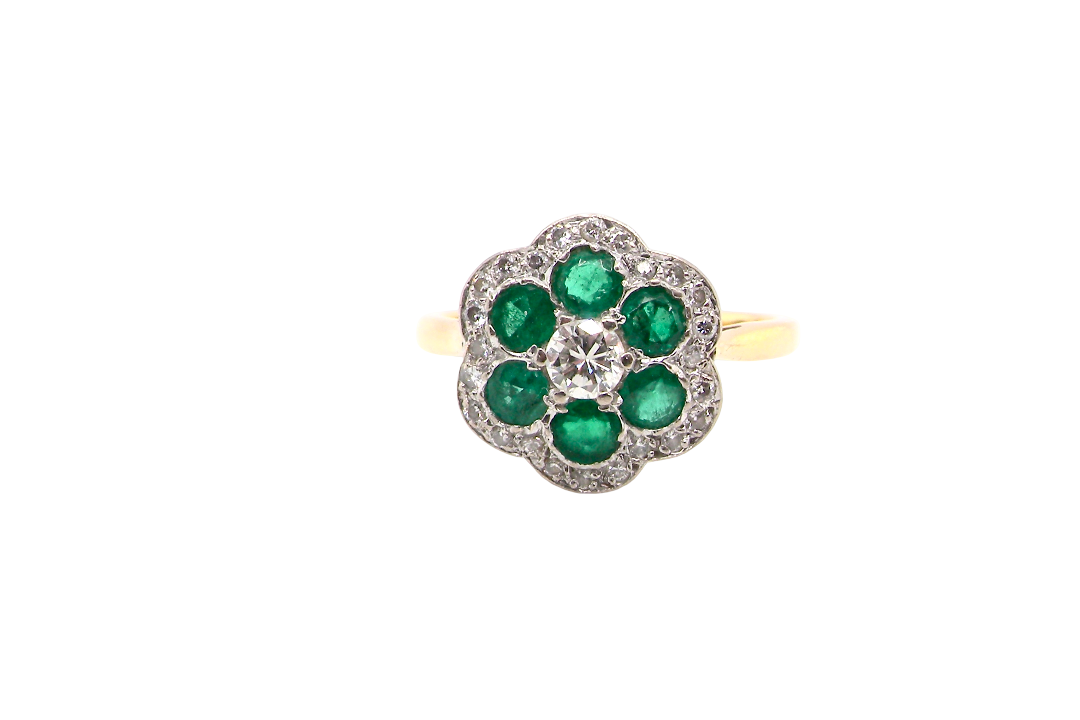 A pretty cluster ring. Features emeralds and diamonds. Centre stone a brilliant cut white diamond, measures 4mm (0.25 carats). 